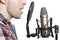 Record voice to microphone in studio. young man sings in studio condenser microphone with spider isolated on white background