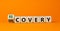 Recovery or discovery symbol. Turned a wooden cube, changed a word `discovery` to `recovery`. Beautiful orange background.