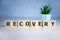 RECOVERY word concept written on wooden cubes lying on a light table and light background