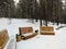 Recreation area with new wooden benches in a winter park with coniferous trees. Noyabrsk, Russia