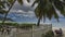 In the recreation area on a tropical beach, behind a white fence, there is a wooden table, benches