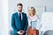 Recruiter with clenched hands and blonde woman with clipboard standing in office