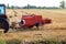Rectangular baler discharges straw bale in a field during the harvesting process