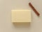 Rectangular bar of soap and cinnamon stick on beige background