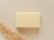 Rectangular bar of soap and dry plant on beige background