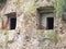 The rectangular entrances to Etruscan tombs carved in the wall of a tufo cliff