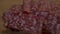 Rectangular pieces of salami on a rotating wooden surface. Sausage close-up. 4k video. Food on the chopping board