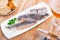 on rectangular plate salted herring fillet cut into pieces with onion rings and sprig of parsley