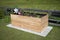 Rectangular raised bed made of wood on granite stones with small plants