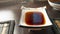 Rectangular Soy Sauce Dipping Dish on a Dark Table with Bamboo Dining Mats. Chopstick Rest, Bowl in Blurred Background. Warm Glow