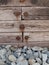 Rectangular wooden planks fastened with rusty large nails and pebbles on the ground