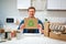 Recycle symbol. Young smiling man holding cardboard with recycle icon while sitting at the table with other waste at