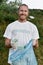 Recycling concept. Vertical shot of a smiling young man, male volunteer wearing uniform and rubber gloves collecting