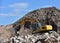 Recycling concrete and construction waste from demolition. Excavator at landfill of the disposa. Reuse of building rubble. Backhoe