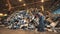 Recycling factory worker sorts garbage into a pile.