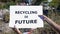 Recycling is future phrase on cardboard in hands against landfill background