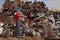 Recycling industry, worker using phone at heap of old metal