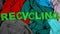 Recycling made of letters on multicolored textile background, overconsumption