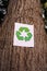 Recycling sign on the trunk of a tree