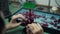 Red accessory on table in workshop with jeweller working indoors. Unrecognizable Caucasian woman making decoration in