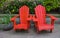 Red Adirondack chair setting at the garden. Traditional curveback red wooden beach chair