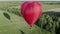 Red air love balloon in heart shape flying over green field at sunny day