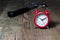 Red alarm clock and hammer on the wooden table