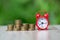 A red alarm clock and a pile of coins resting on the table. The concept of scheduling work, business investments. Planning