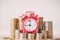 Red alarm clock on stack of coins in concept of savings and money growing or energy save.