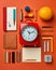 a red alarm clock surrounded by school supplies on an orange background