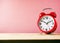 Red alarm clock on wooden pink background