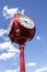 Red antique four sided street standing clock against blue sky with fluffy clouds - vertical