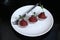 Red appetizing Tartar sauce in three pialas on a plate with a knife and fork, decorated with a stem of sprouted green peas, close-