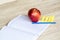 Red apple, blue pen And a white note book with a wooden background,selective Focus