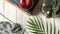 A red apple on books on a gray background next to a flower pot and knitting