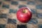 Red apple on a checked wooden board, concept