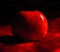 Red apple on a crimson velvet backdrop, illuminated by soft, ambient lighting