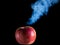 Red apple with cuts on a black background is smoking