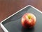 red apple on grey digital weight scale on dark brown wooden floor