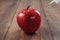 Red apple injecting a needle or syringe and chemical pesticides on a wooden background. Specific pesticide residues in apples,