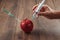 Red apple injecting a needle or syringe and chemical pesticides on a wooden background. Specific pesticide residues in apples,