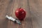 Red apple injecting a needle or syringe and chemical pesticides on a wooden background. Specific pesticide residues in apples,