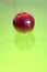 Red apple over a green reflective surface