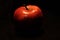 Red apple partially lit with dark background