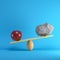 Red apple and Rock playing on yellow seesaw on blue background