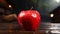 A red apple sits on a wooden table
