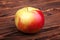 A red apple on a wooden background. A colorful and sweet apple. A healthful and nutritious snack. A single organic ingredient.