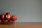 Red apples in an aluminum sieve container on wooden table and grey background.