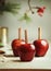 Red apples with cinnamon sticks on kitchen table with sugar at wall background with fir green. Sugar glazed apples. Delicious