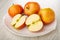 Red apples, halves of apple in white dish on wooden table